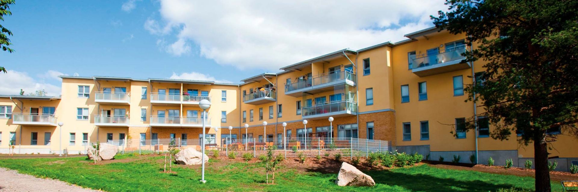 Palvelutalo Elsie, monikerroksinen rakennus, jossa on parvekkeita ja vihreä piha rakennuksen edessä.